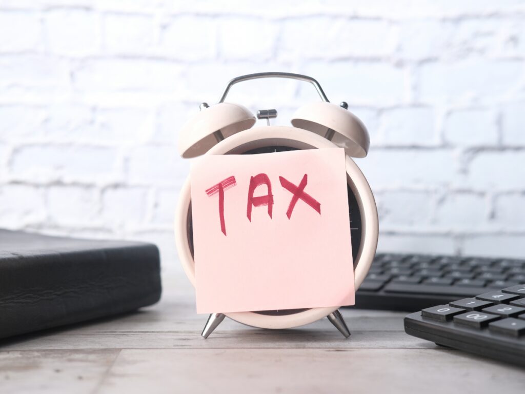 An alarm with a pink post it and the words TAX in red