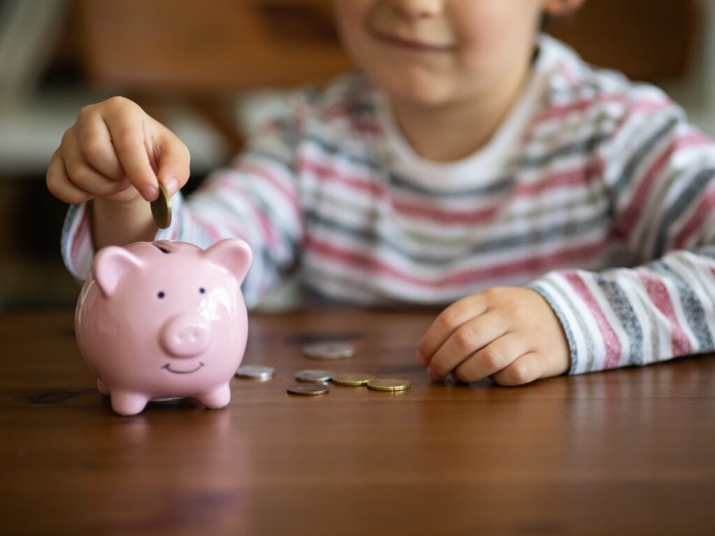Child putting coin in piggy bank